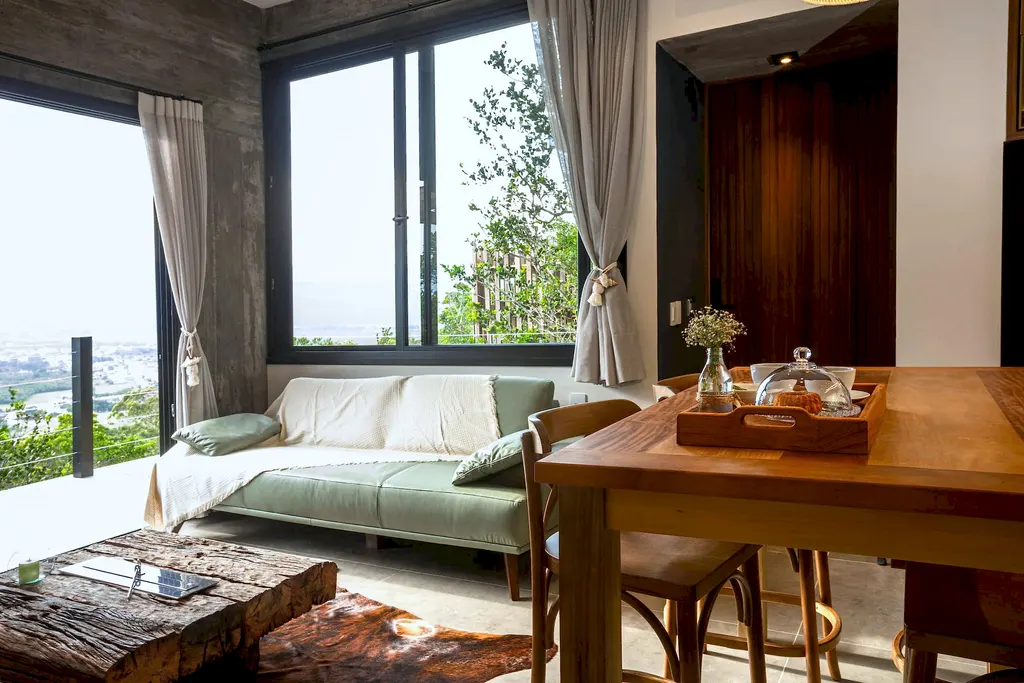 Sala de estar do Espaço Bosque com sofá, bandeja de café e janela para a mata