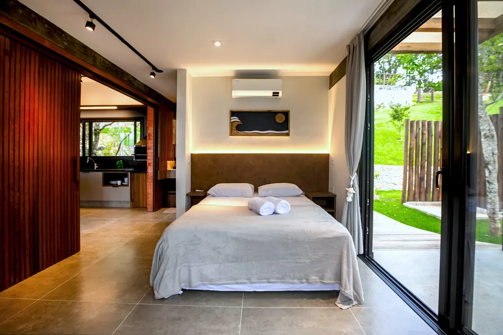 Quarto amplo do Espaço Bosque com painel de madeira e acesso ao jardim