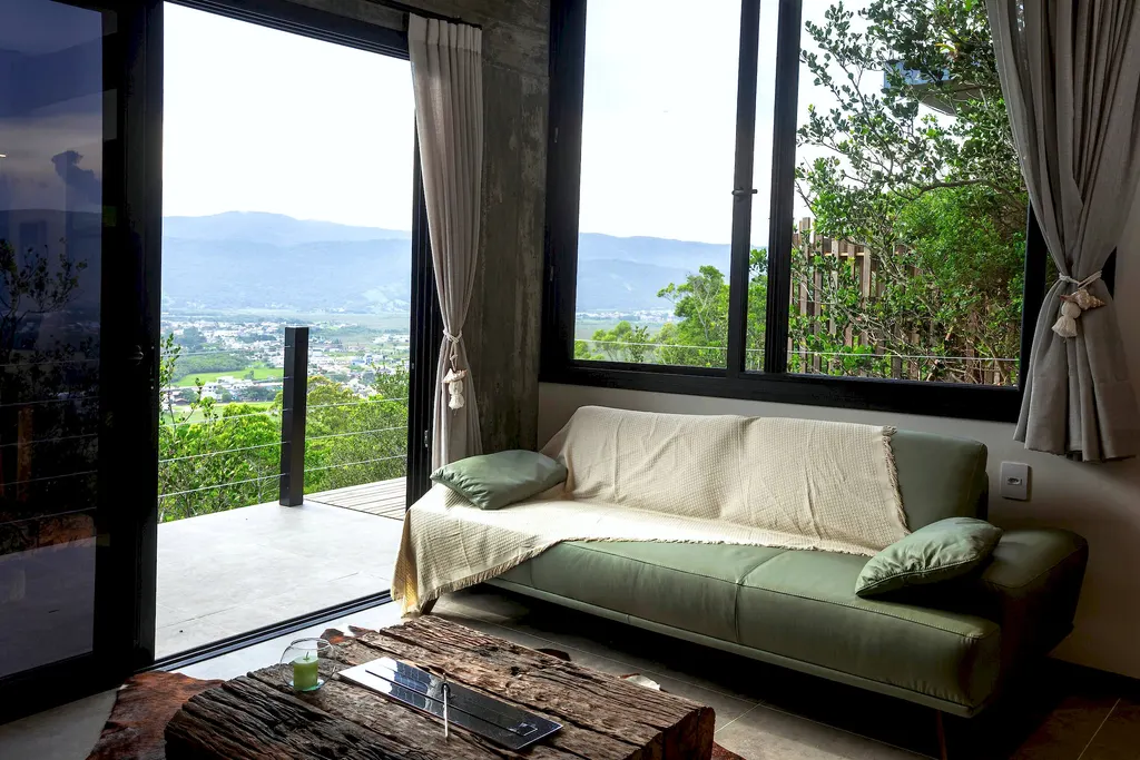 Sofá verde junto à janela com vista para as montanhas