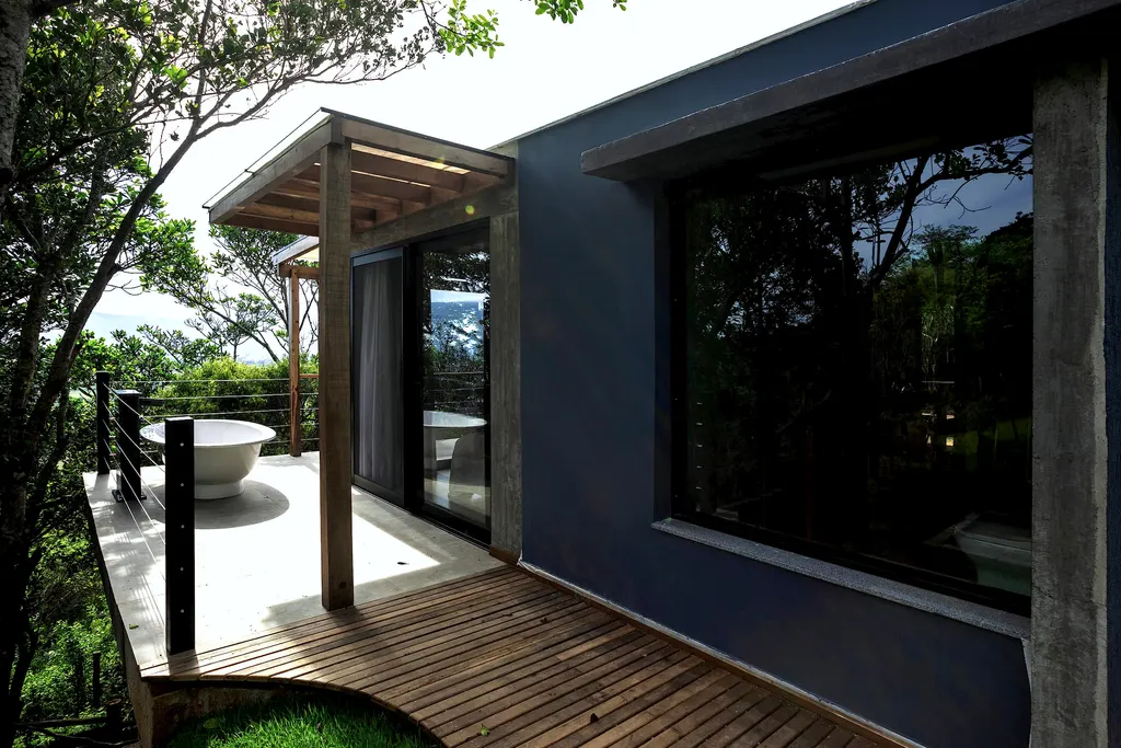 Fachada azul do Espaço Bosque com deck e banheira externa