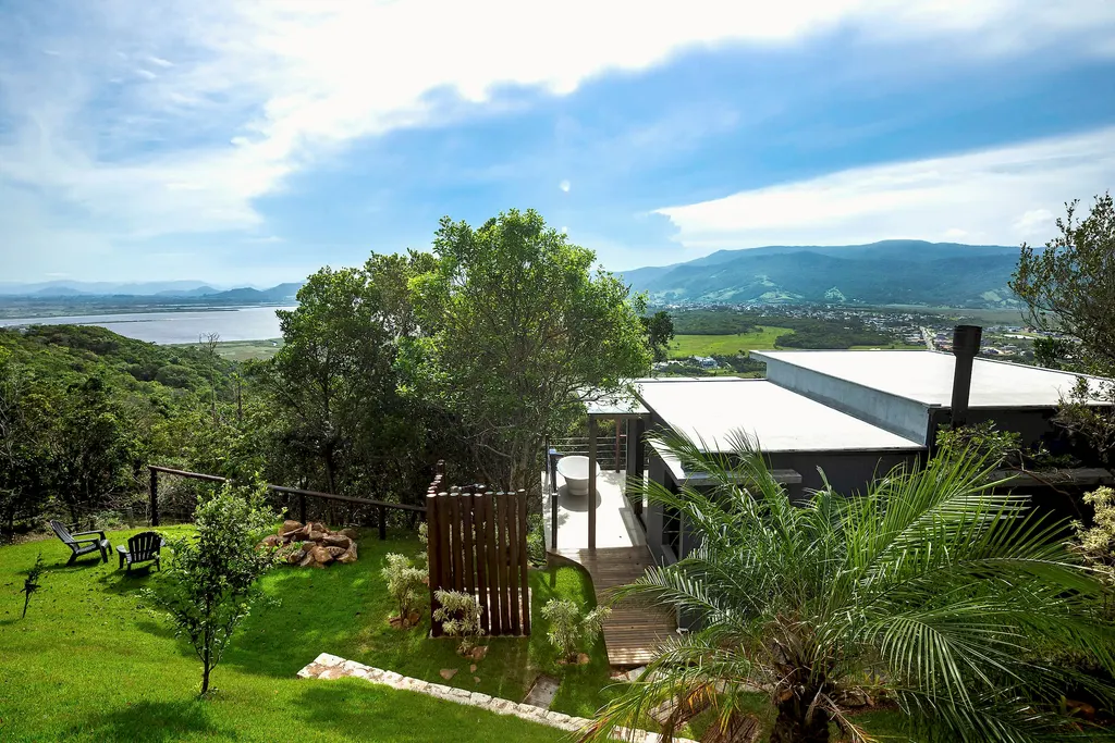 Vista do alto do refúgio com as casas, a mata e a lagoa ao fundo