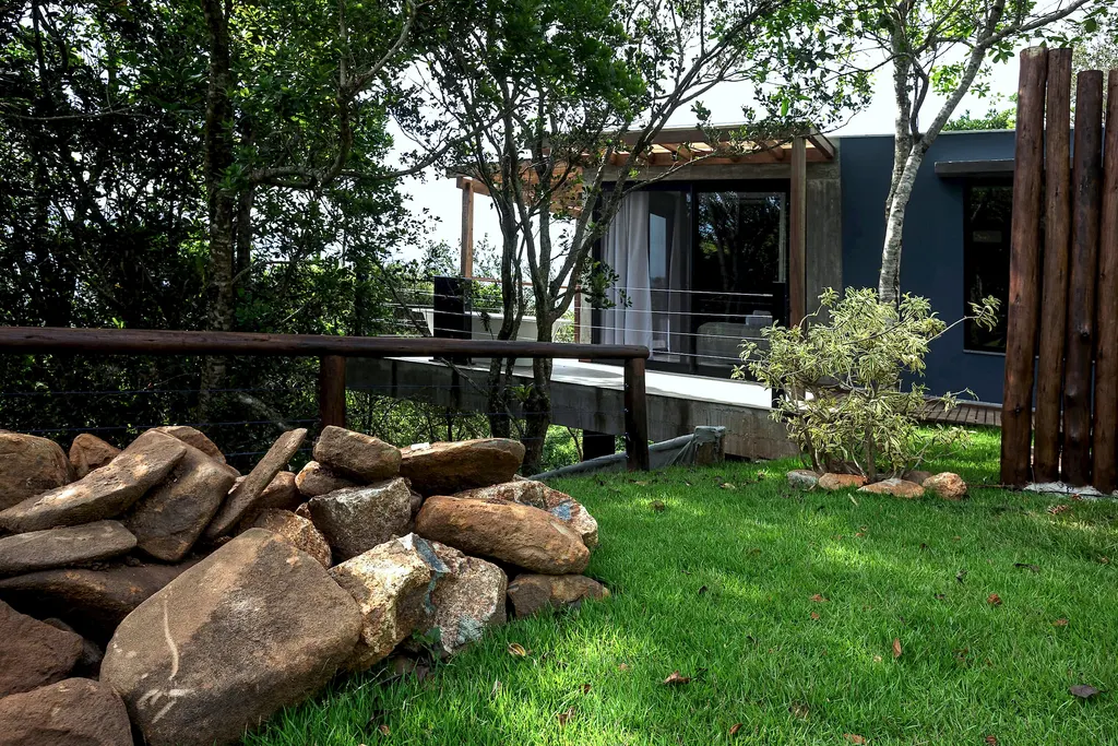 Jardim com pedras e a casa do Espaço Bosque entre as árvores
