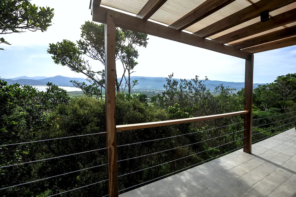 Deck com pergolado de madeira e vista para a mata e a lagoa