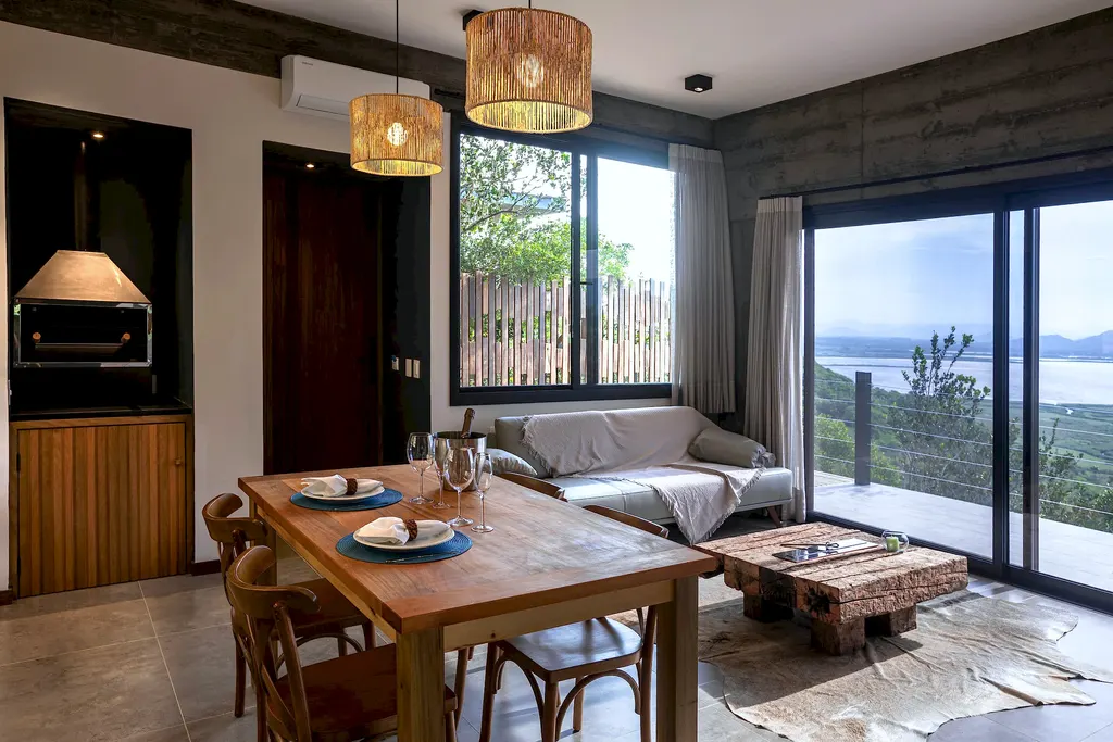 Sala e cozinha integradas do Espaço Lagoa com mesa de madeira e janela para a lagoa