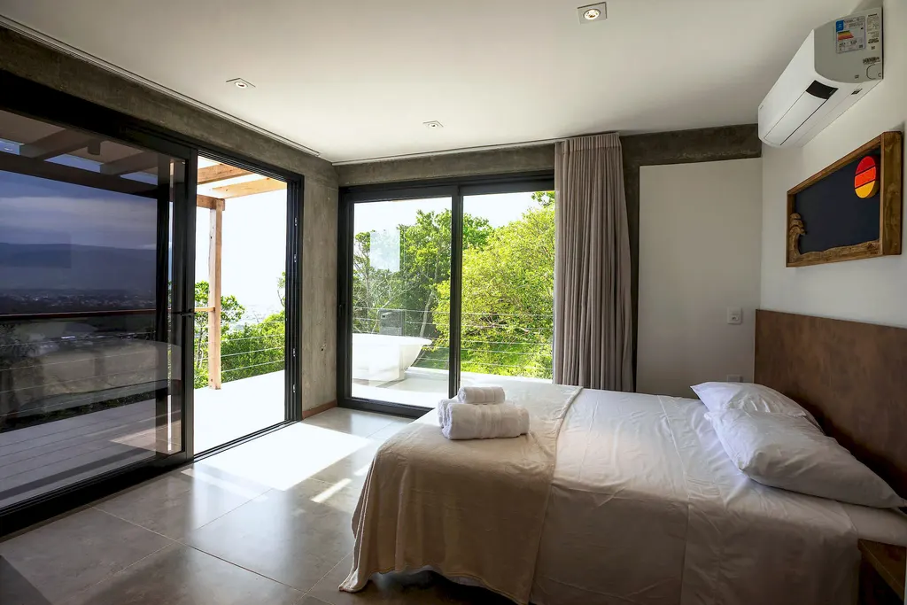 Cama de casal com janelas amplas para a mata e a vista