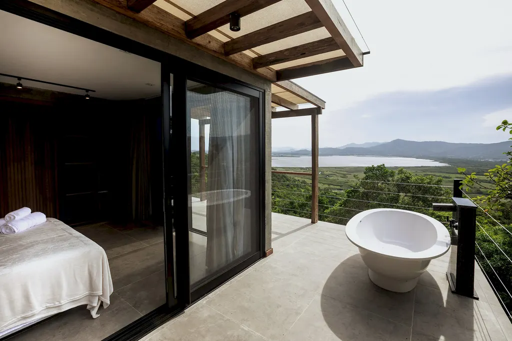 Quarto integrado ao deck com banheira externa e vista para a lagoa
