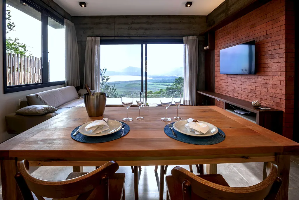 Mesa de jantar posta com vista para a lagoa pela porta de vidro