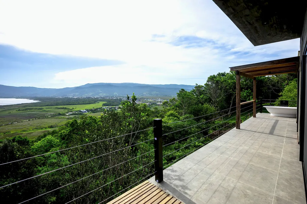 Deck suspenso sobre a mata com vista para a lagoa e a serra