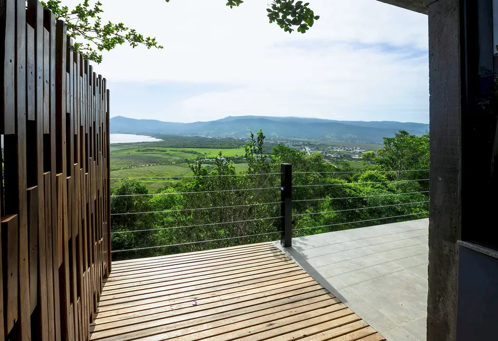 Deck de madeira com guarda-corpo de cabos e vista aberta para o vale