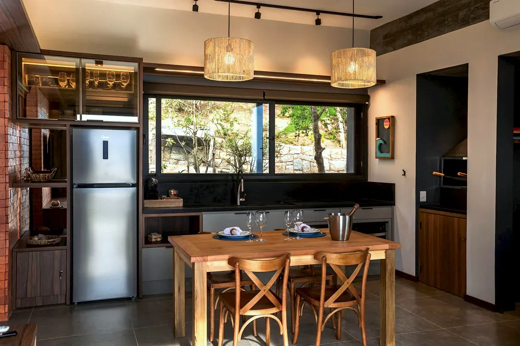 Cozinha equipada com geladeira inox, bancada escura e mesa para seis