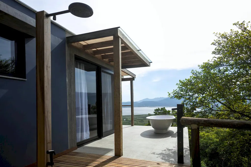 Chuveiro externo e banheira no deck com a lagoa ao fundo
