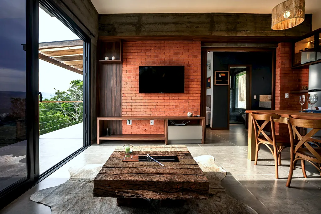 Sala com mesa de centro rústica, parede de tijolos e porta para o deck