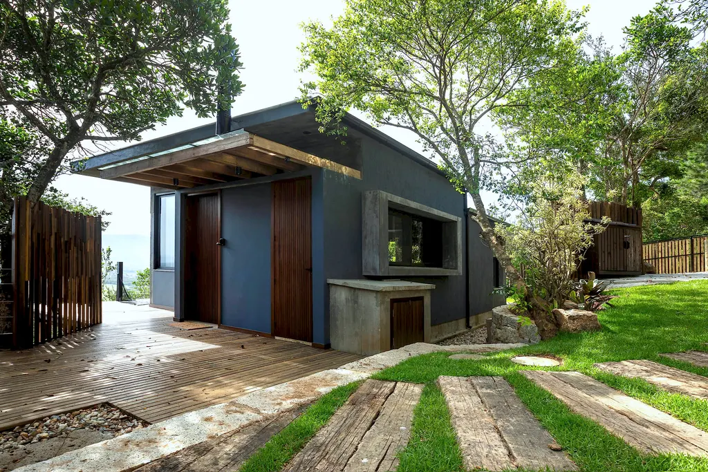 Casa azul entre árvores com caminho de dormentes no gramado