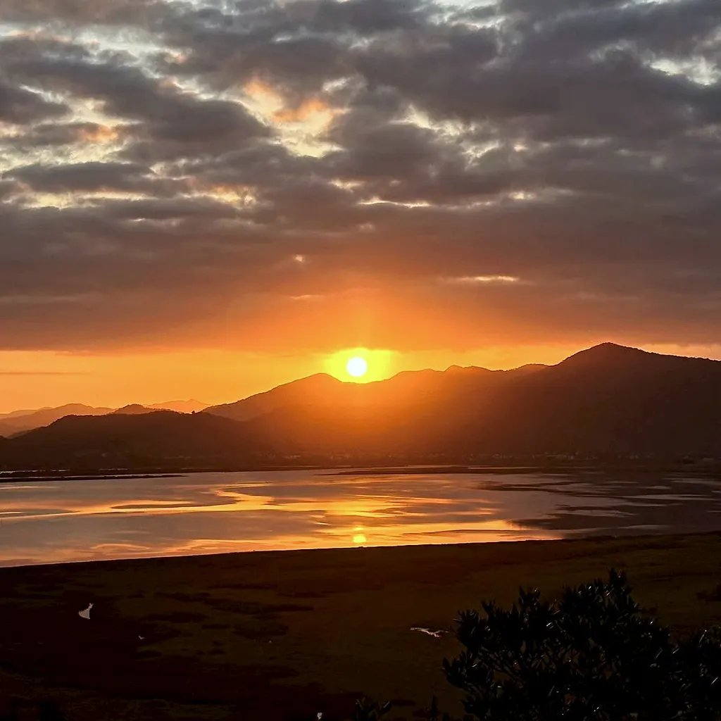 Sol se pondo atrás da serra e refletindo na lagoa, visto do Refúgio da Silveira